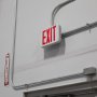 Red MaxLite Exit Light with emergency battery backup mounted over a warehouse door